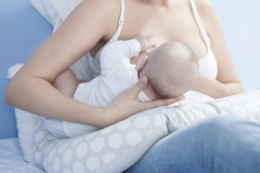 Mother feeding breast with nursing pillow